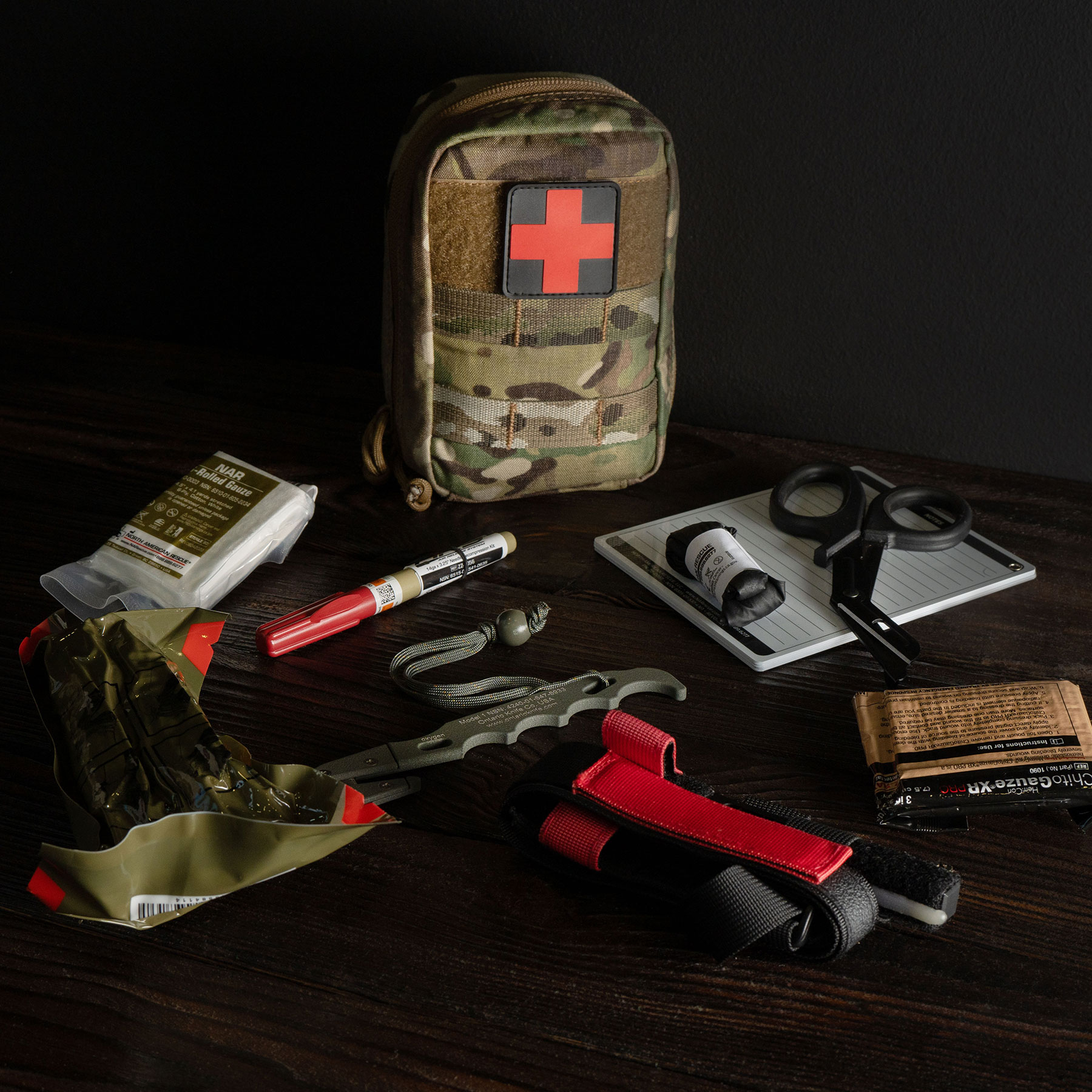 Camouflaged first aid kit with red cross and medical tools on table