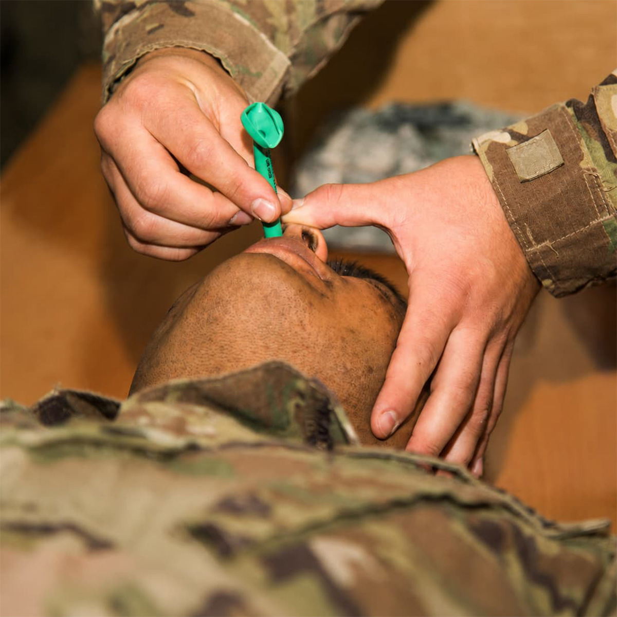 A medic inserts a nasopharyngeal airway into a patient's nostril 