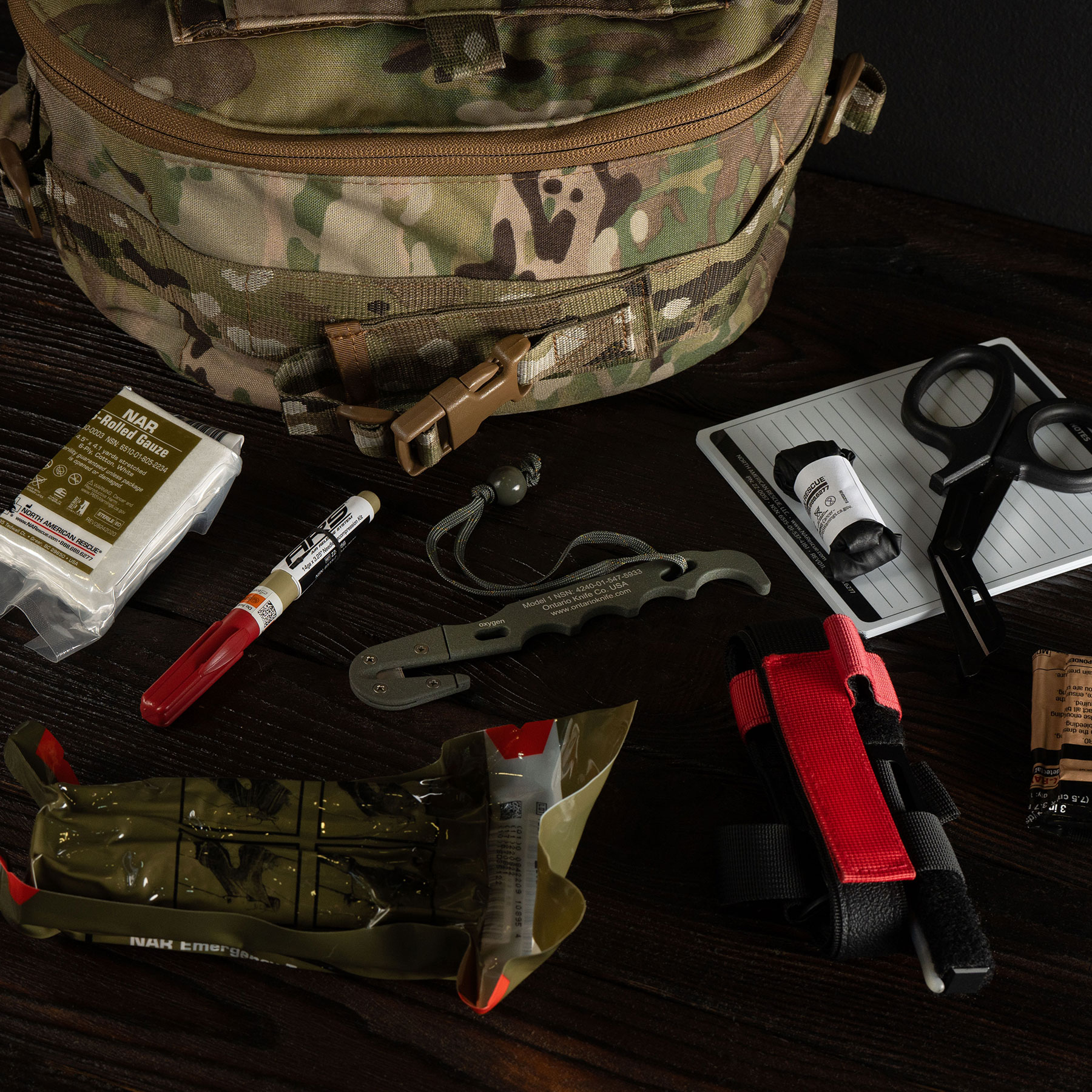 Medical kit with tourniquet, scissors and bandages next to a tactical bag 